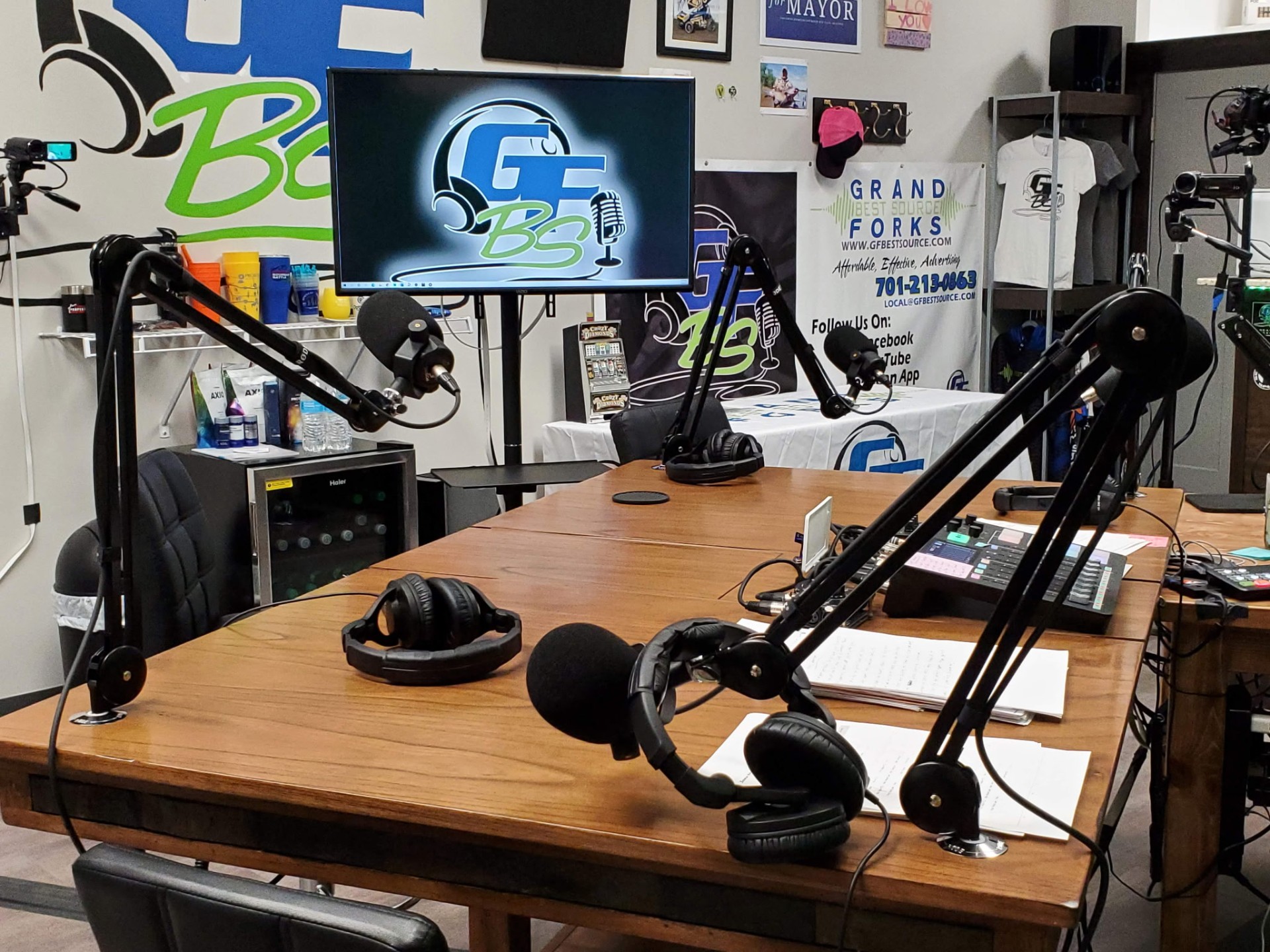 GFBS podcast desk with mics, headphones, and broadcast monitor